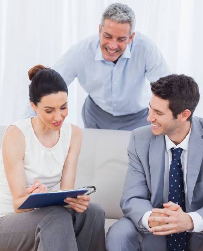 Woman signing a contract as husband and salesman are watching on sofa at home